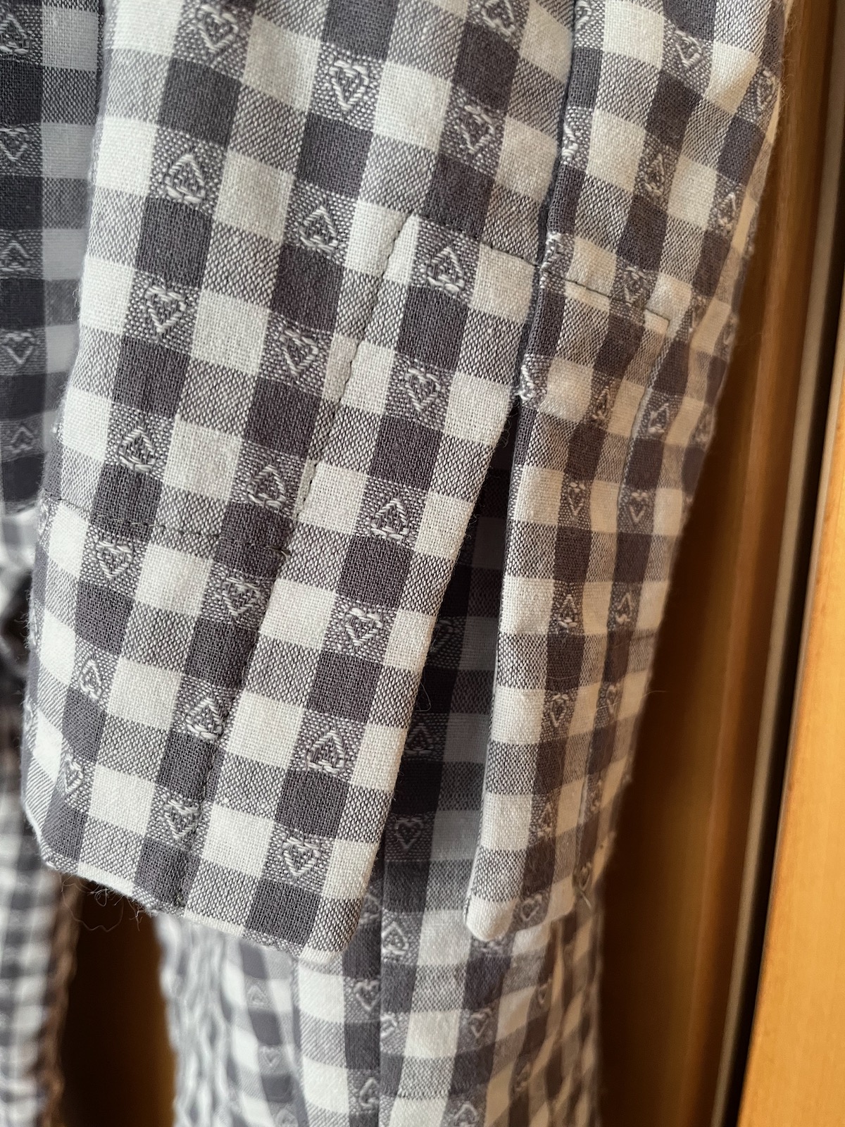 Close up of the hem split of the Fran pyjama top, showing the hem facing and the small jacquard woven hearts in the checked pattern.