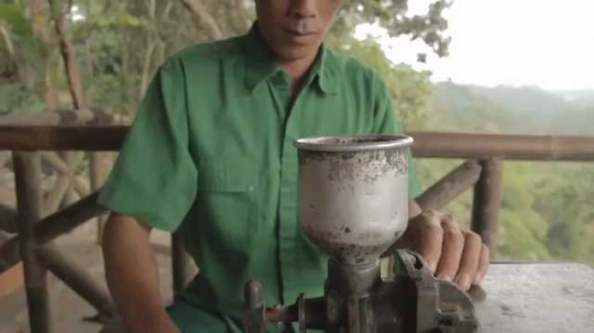 Man Hand-Operating Coffee Grinder, Indonesia, 2010s