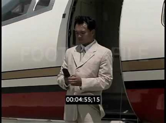 Business Man Talking on Cell Phone in Front of Private Jet, USA, 2000s