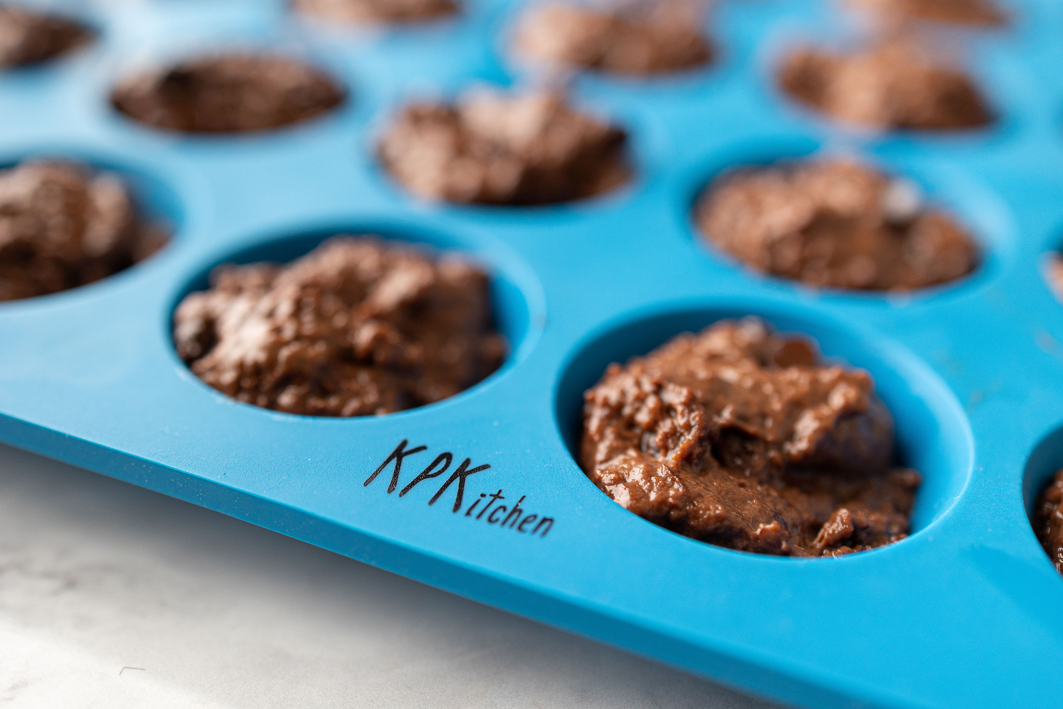 Image of Divide the batter evenly into each muffin cup, filling all...