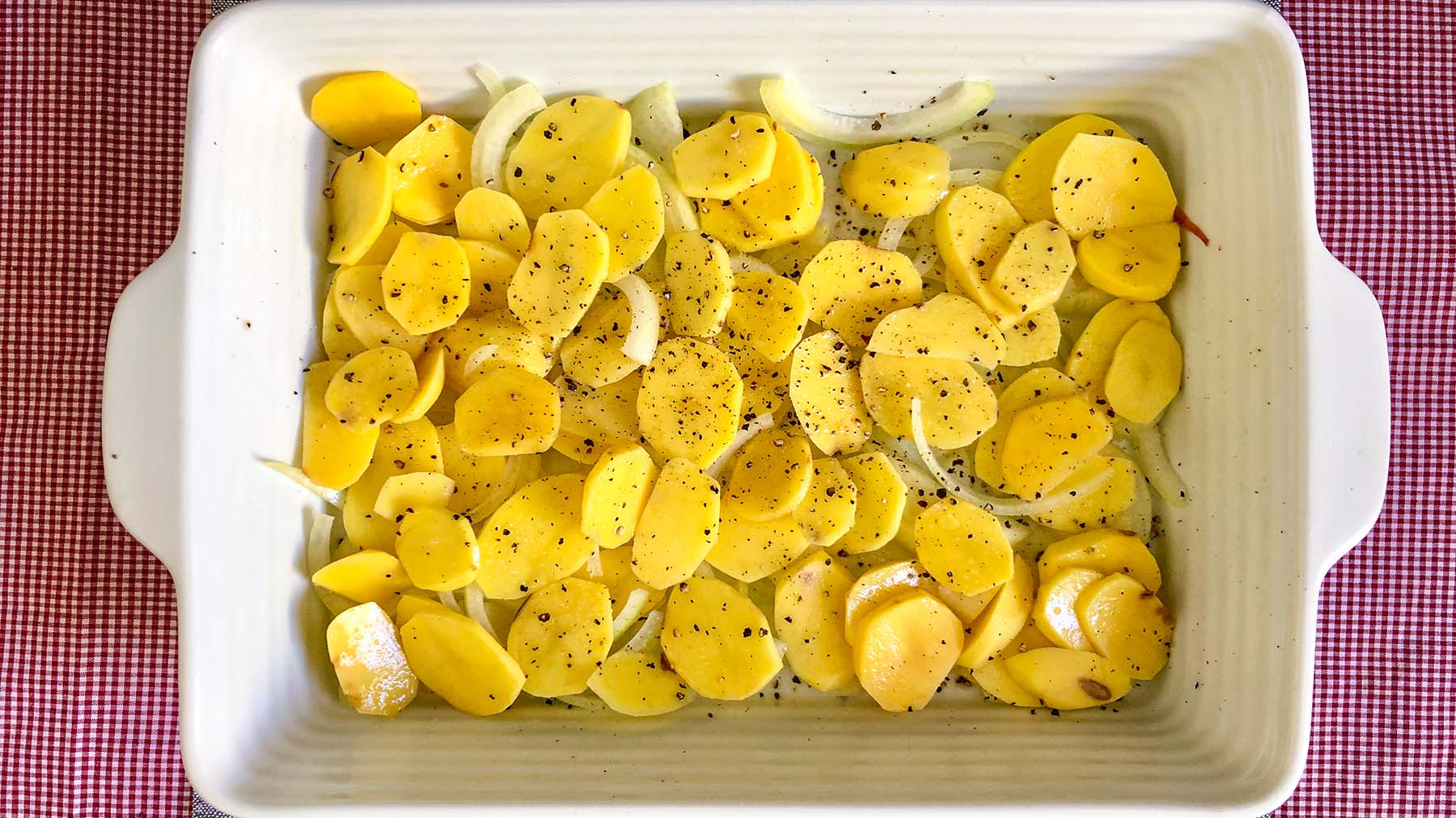 Image of Place sliced onions and thinly sliced potatoes in a buttered...