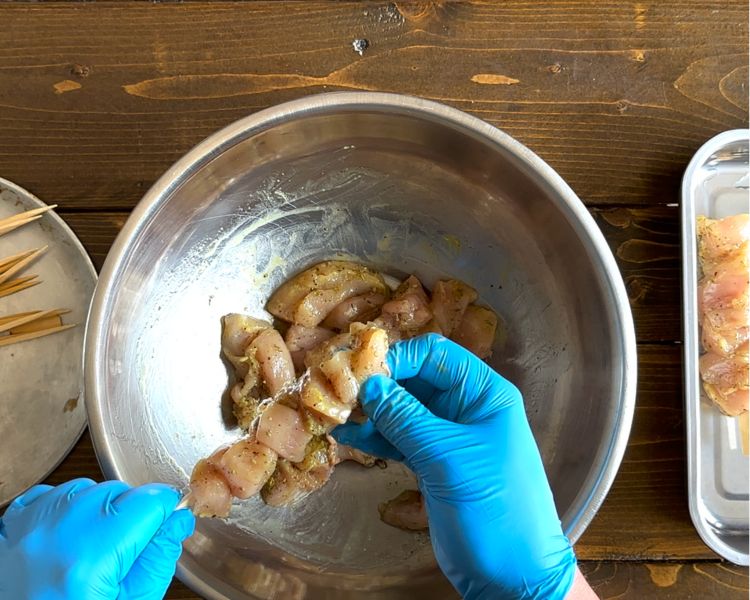 Image of Using wooden skewers soaked in water, carefully skewer the chicken.