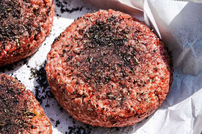 Image of Season the patties evenly with Black & Tan seasoning on...