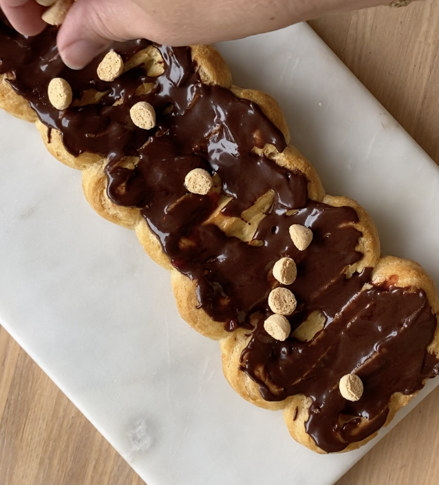 Image of Kom chokolade glasur oven på vandbakkelsen og drys med Amaretti...