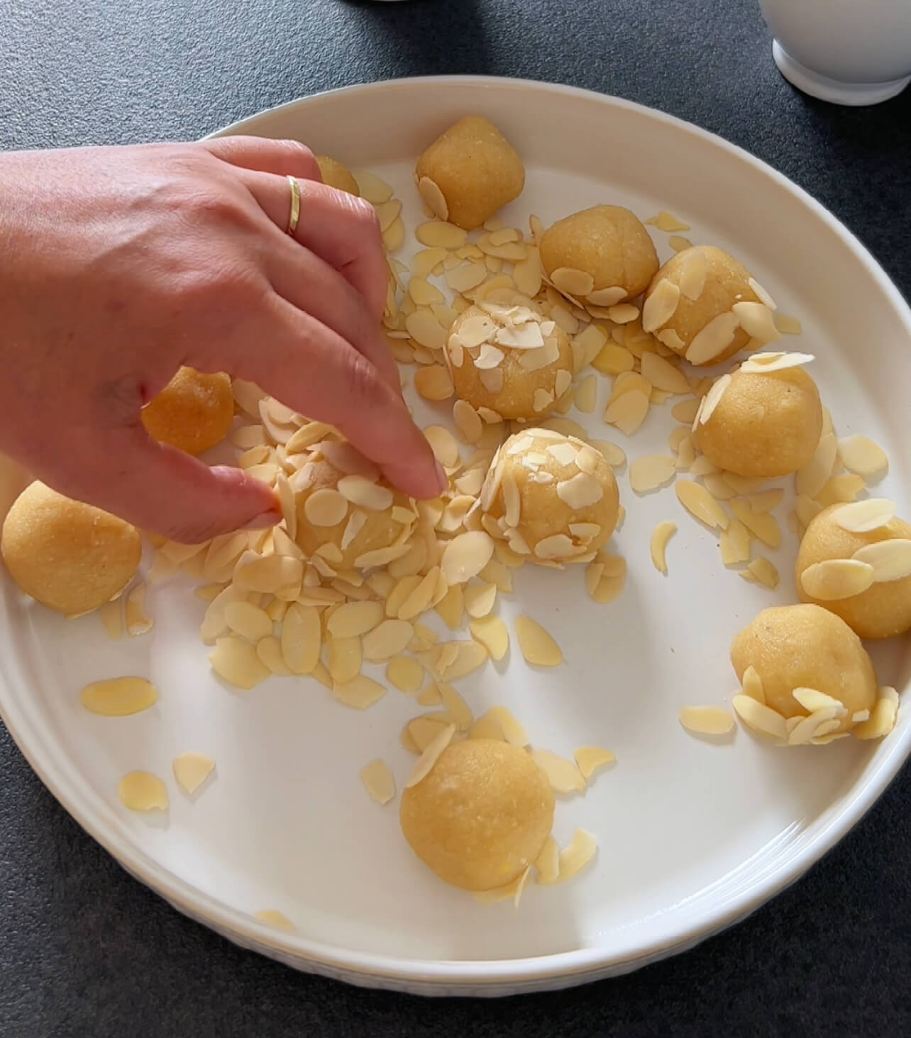 Image of Place the almond-coated balls on the prepared baking sheet.