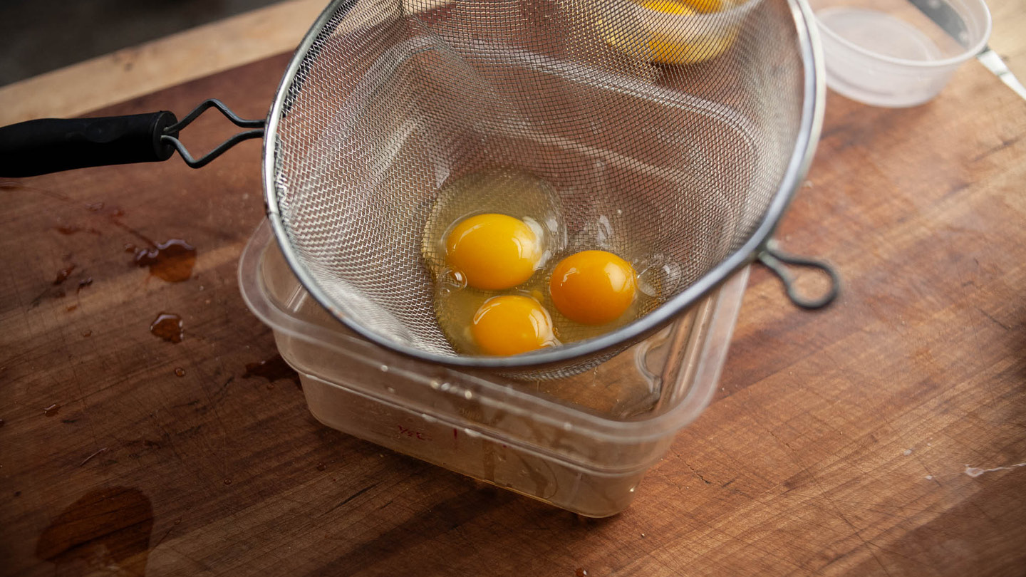 Image of Crack your eggs into a strainer to remove the thin...