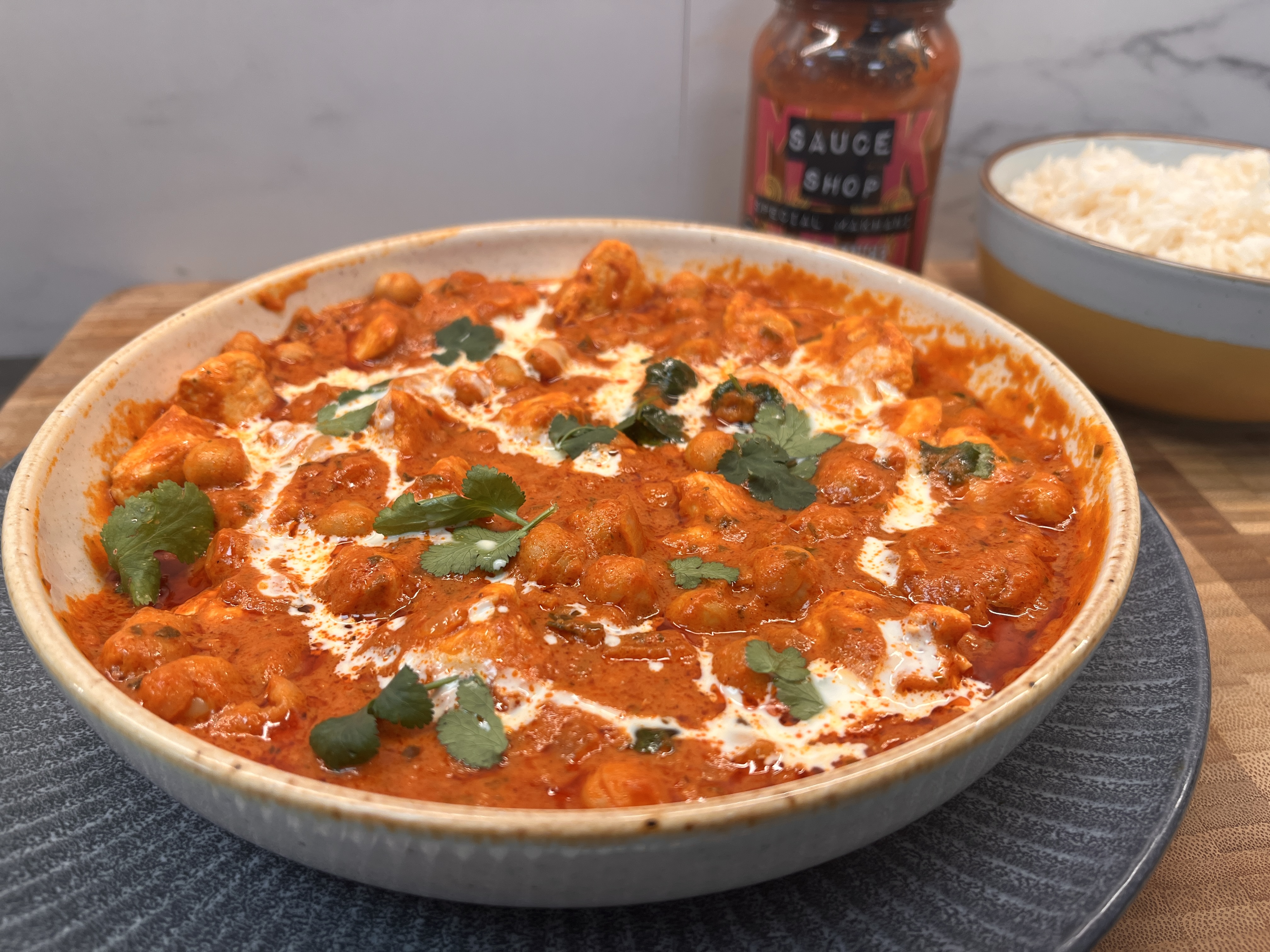  Chicken and Chickpea curry in a white bowl, with white rice and Special Makhani Simmer-Sauce in the background 