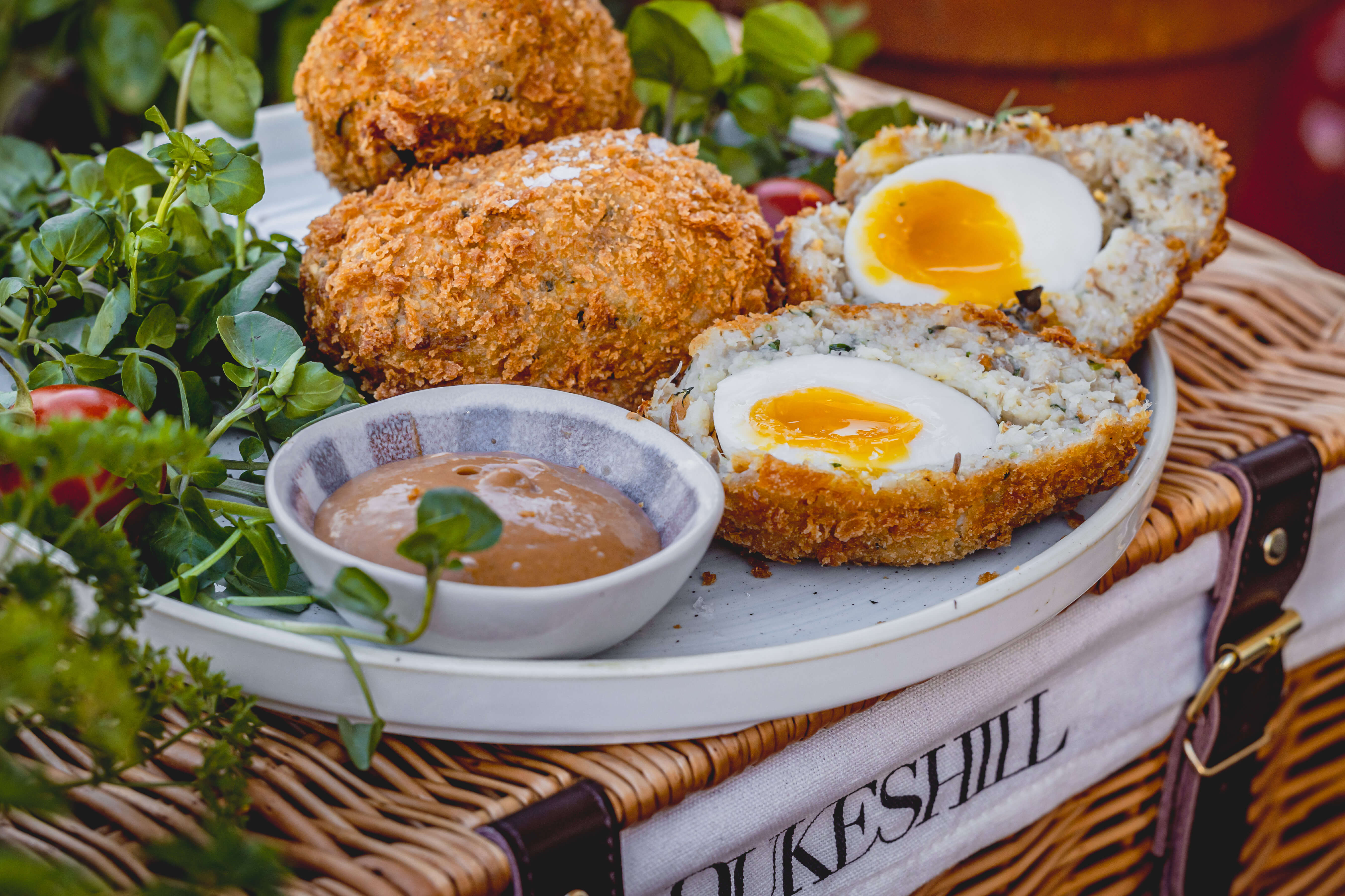 scotch egg cut in half on wicker basket