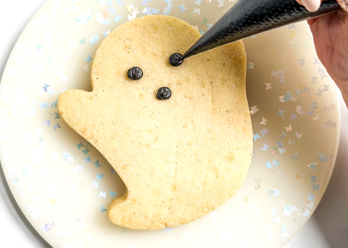 Image of Using black piping consistency icing, pipe three dots representing the...
