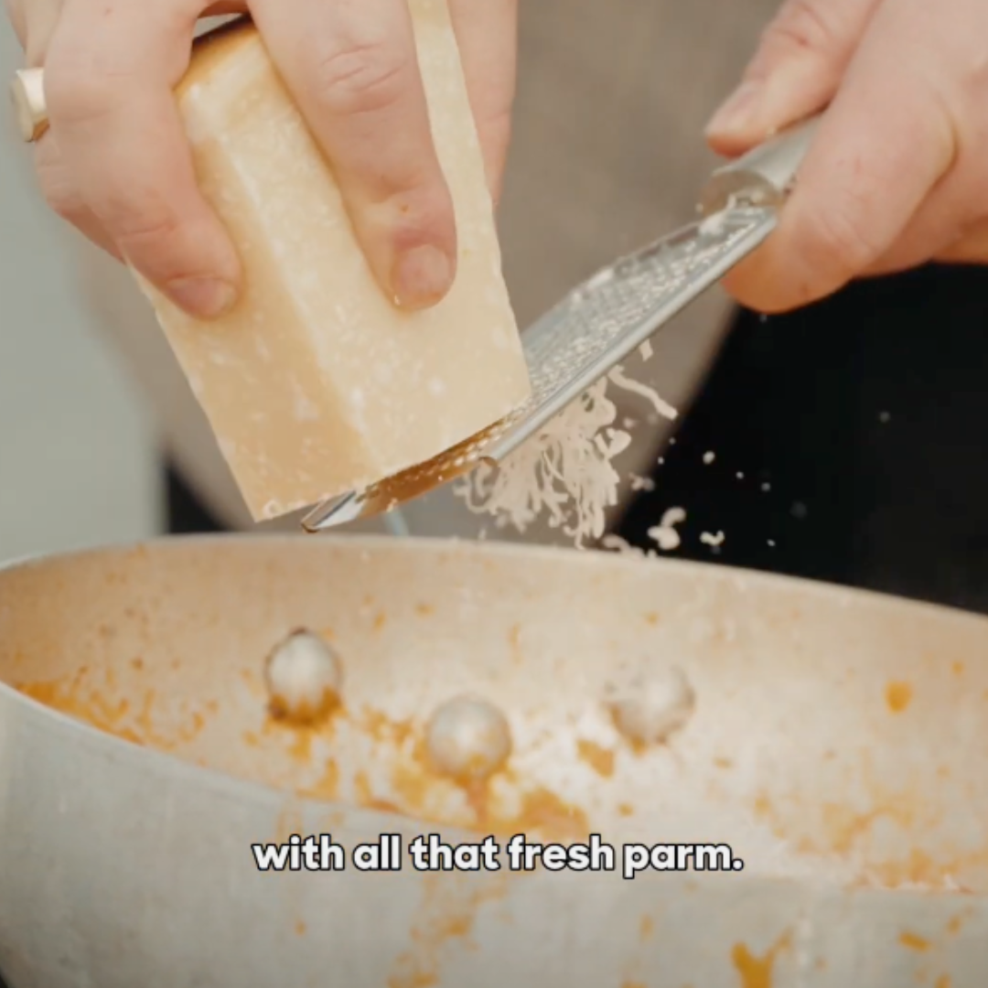 Image of Grate fresh Parmesan directly into sauce sauce and pasta in...