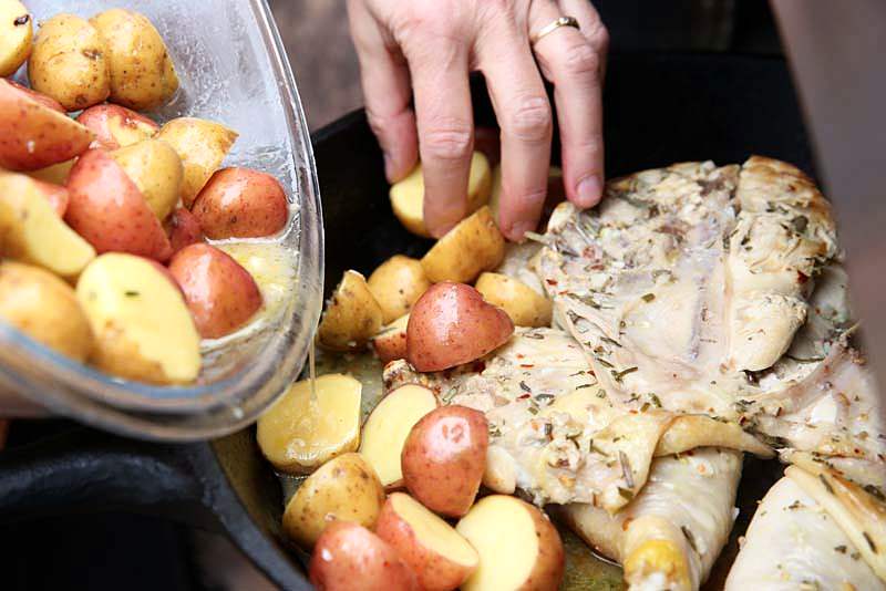 Image of Add the potatoes and place them around the chicken.