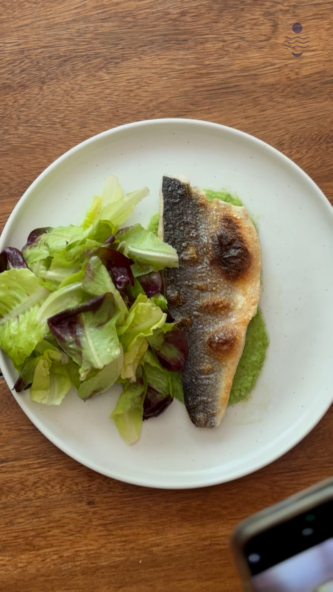 Image of Plate the broiled Branzino on top of the raw green...