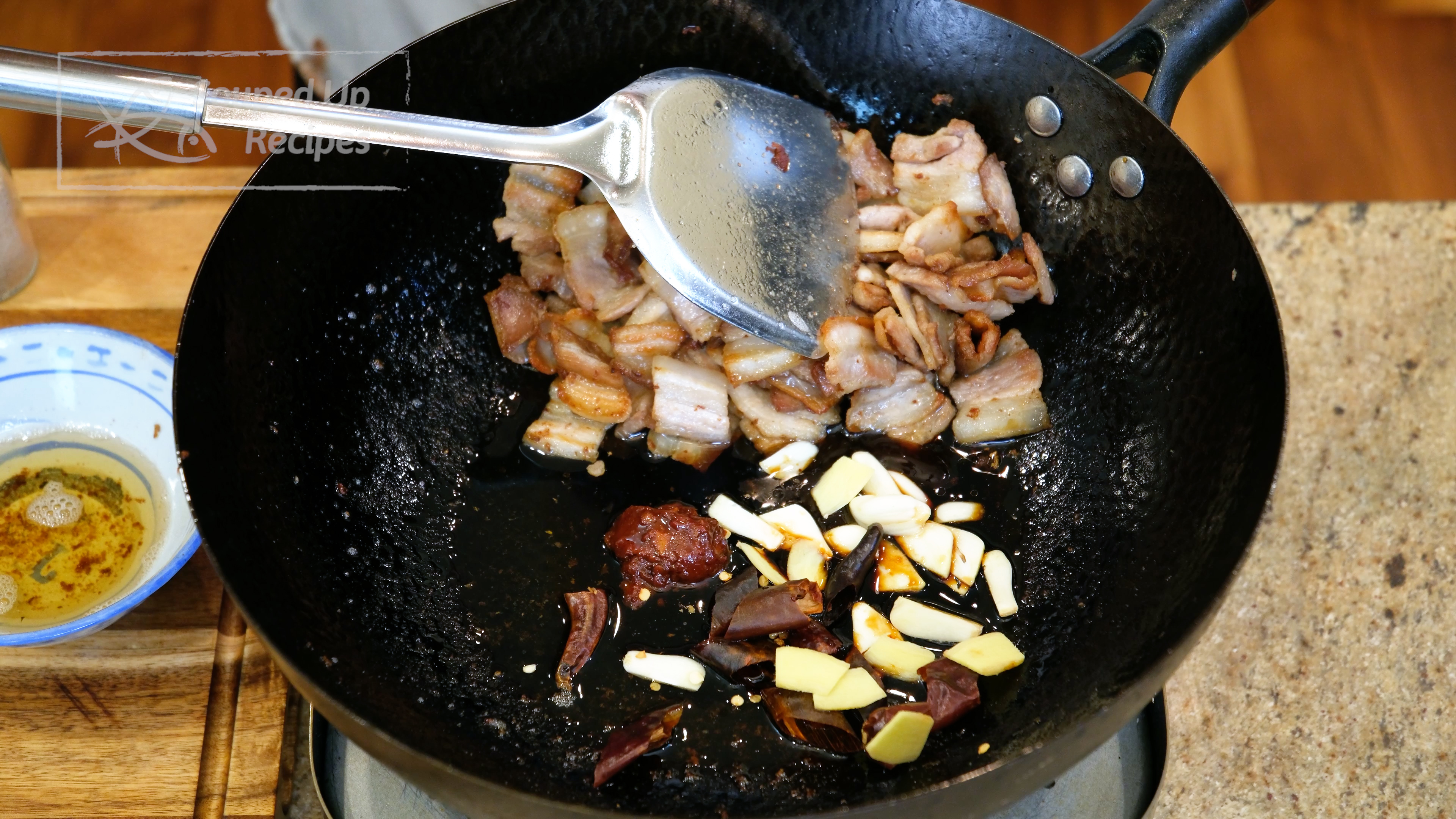 Image of Push the pork to the side and tilt the wok...