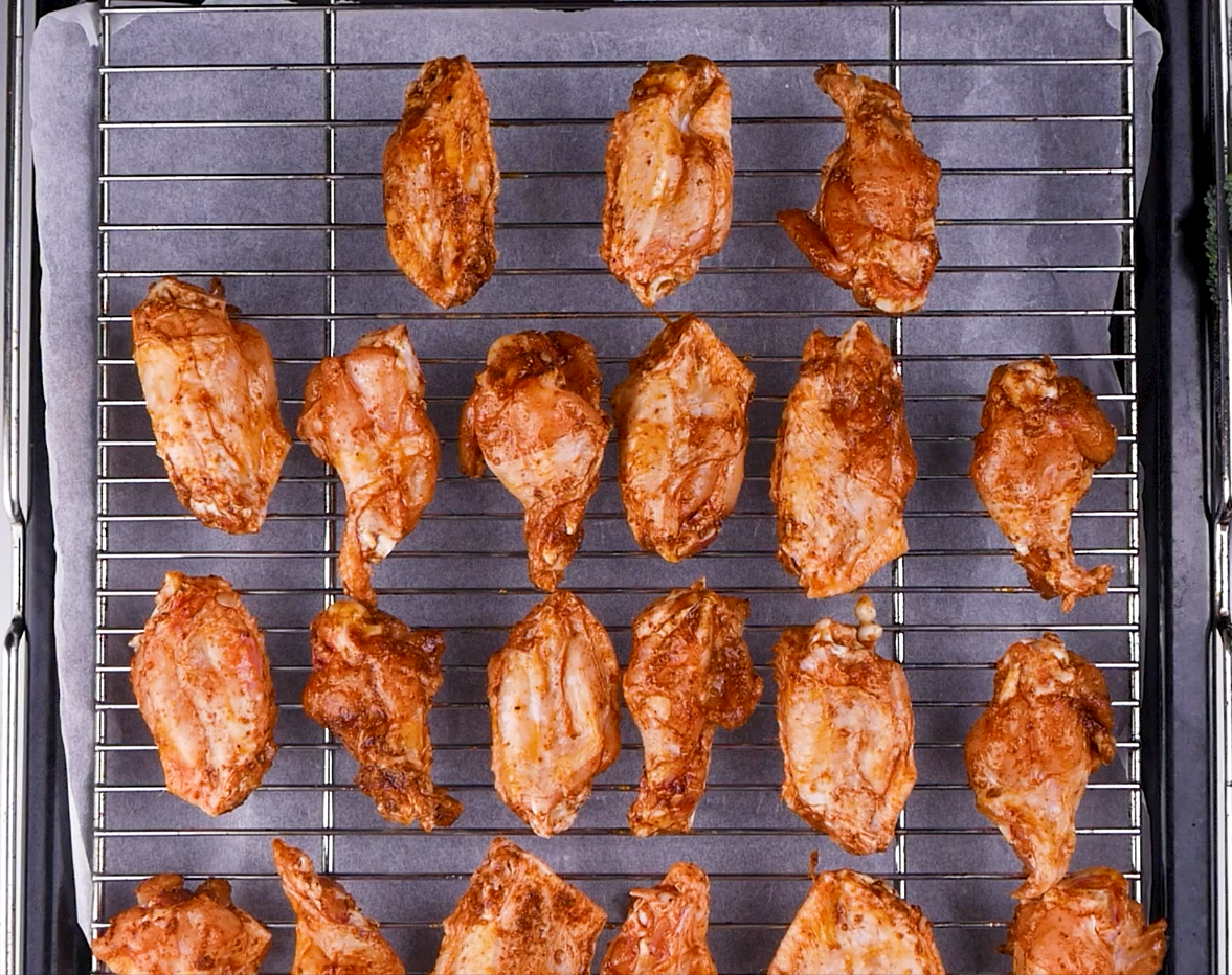 Image of Place chicken wings on rack over a cookie sheet.