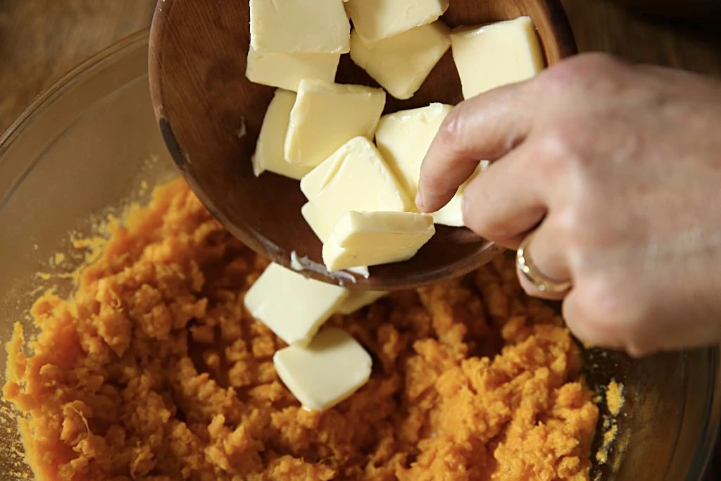 Image of Add 1/2 cup butter to the steaming sweet potatoes.