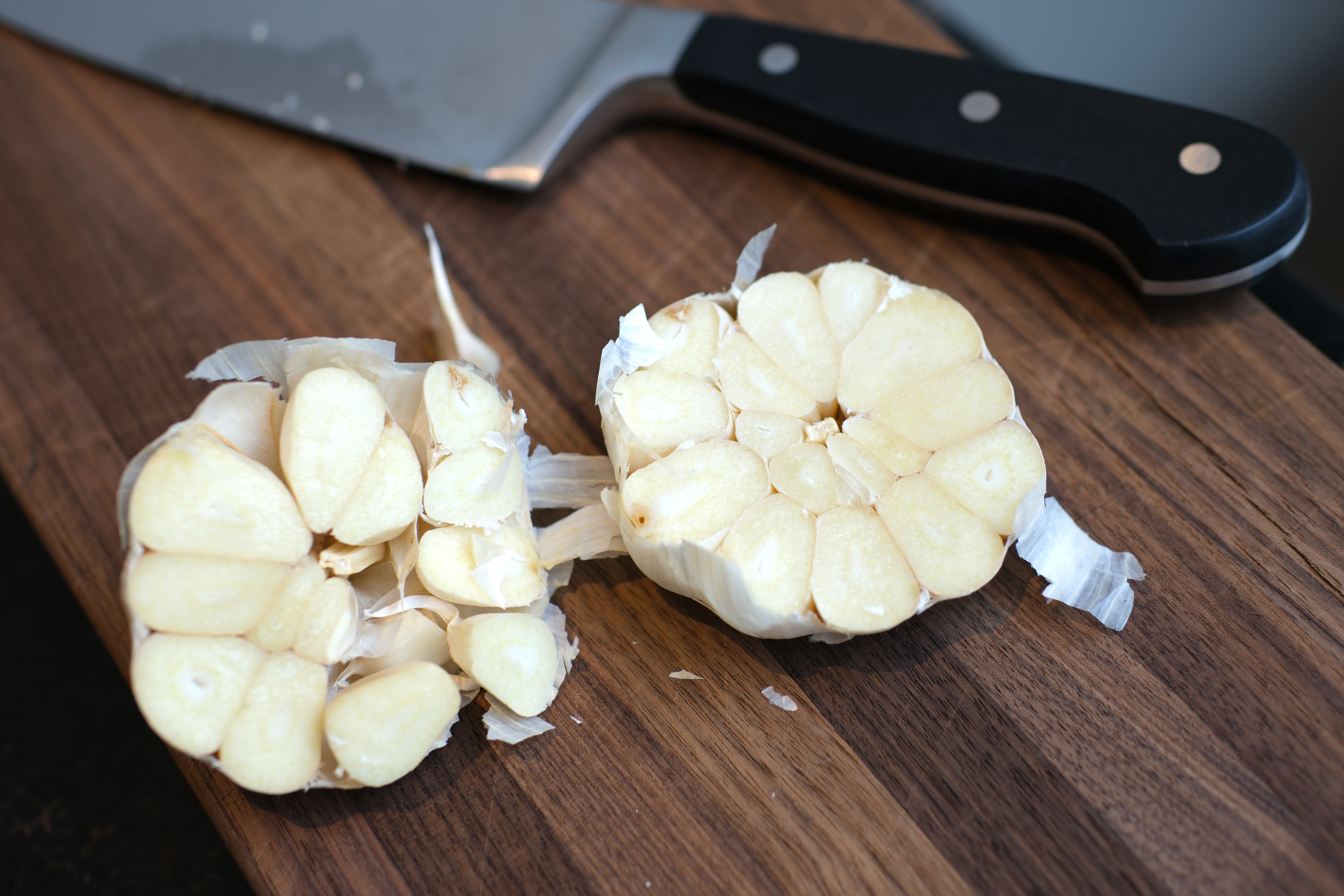 Image of cut the head of garlic in half so each clove...