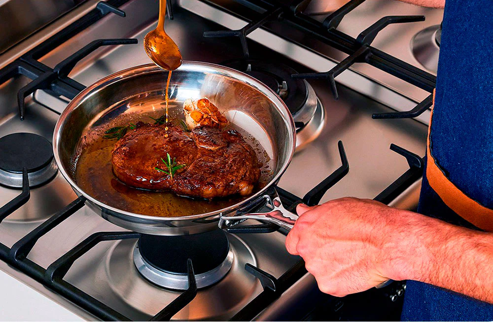 Steak with thyme butter sauce in a stainless steel pan