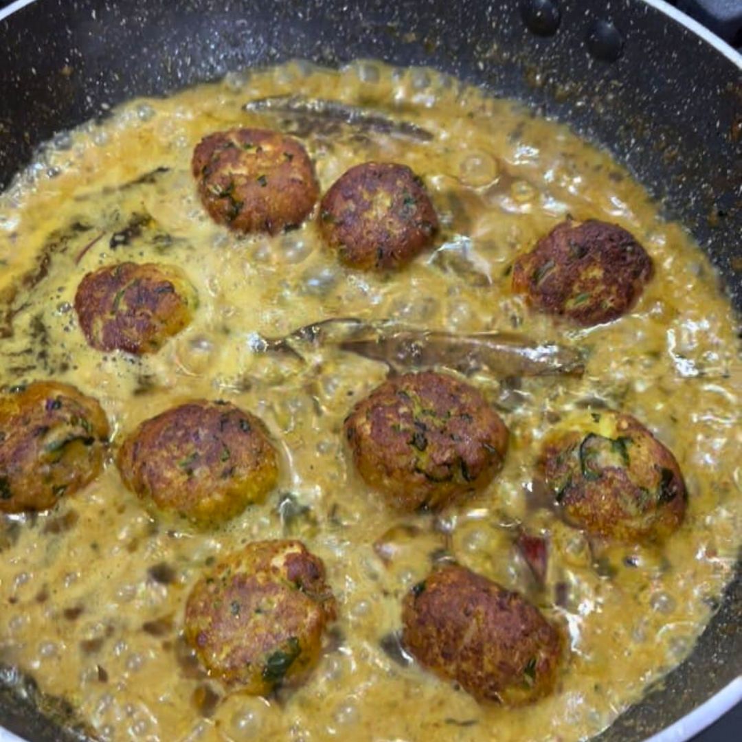 Image of Gently place the fried koftas into the simmering gravy.