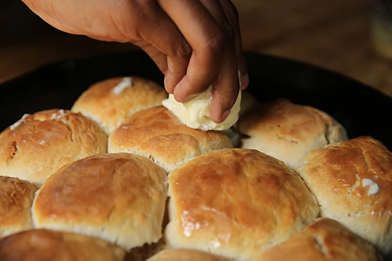 Image of Spread some additional butter over the top of the biscuits.