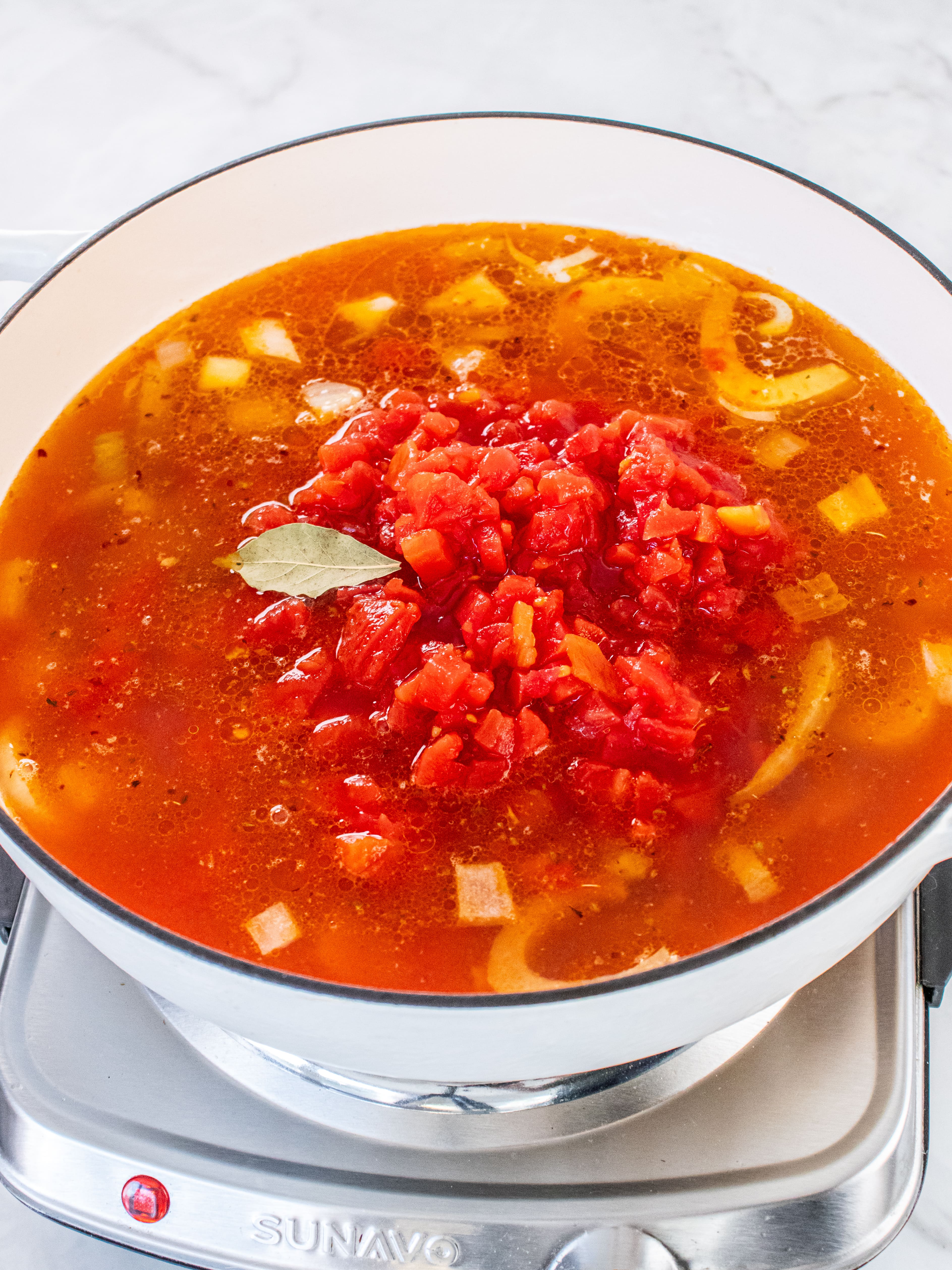 Image of Add broth, clam juice, wine, diced tomatoes, and bay leaf....