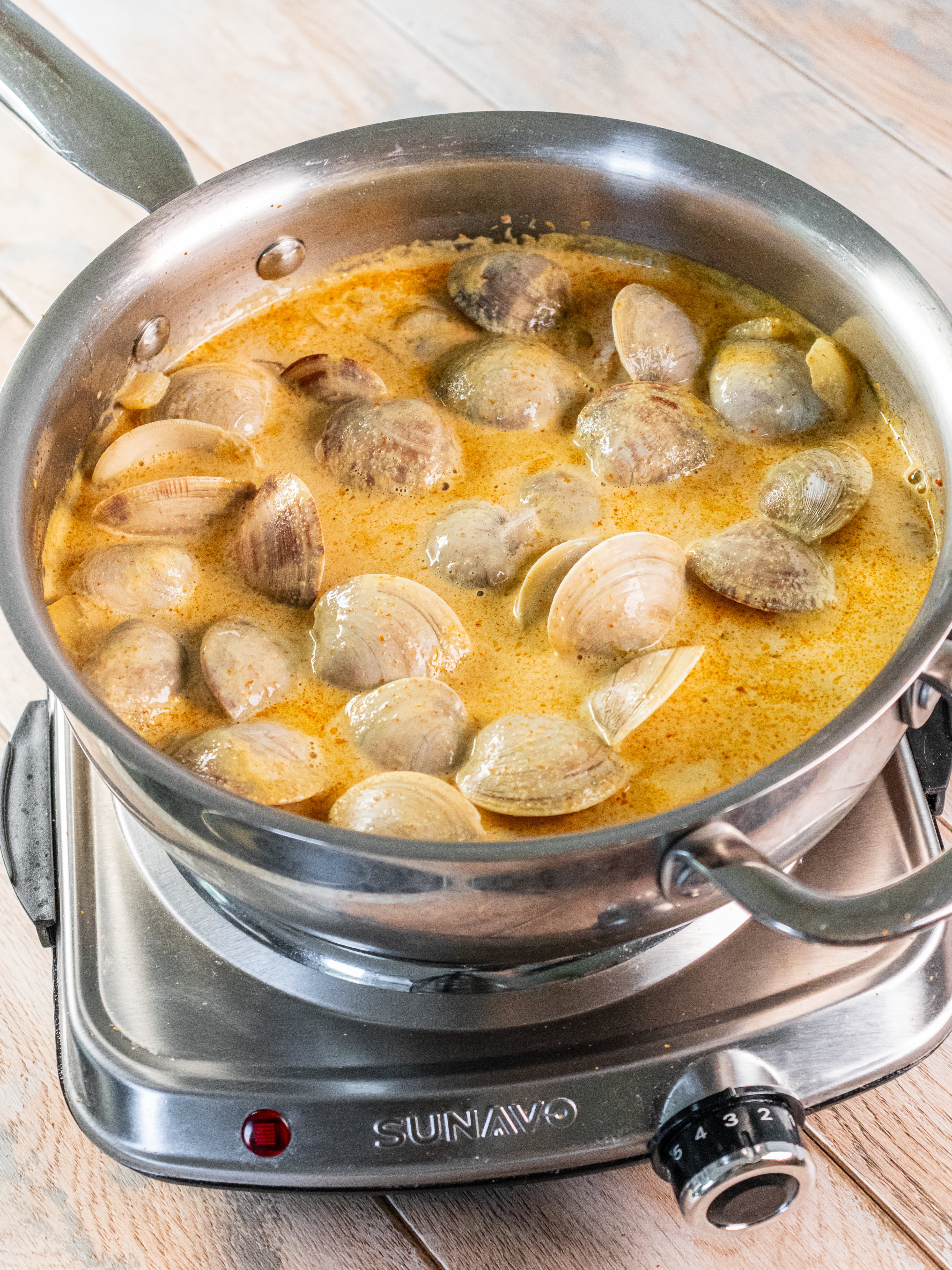 Image of Add the clams to the simmering broth. Cover with lid...