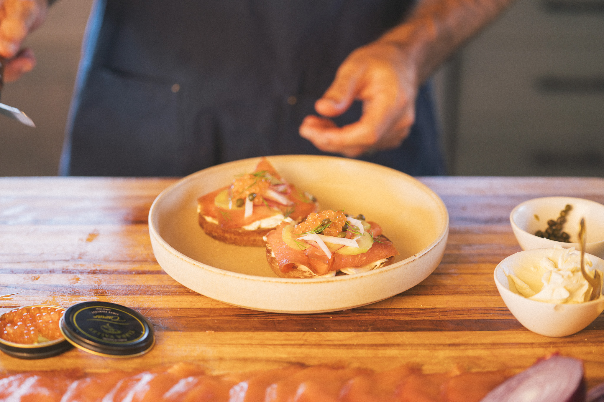 Image of Layer with:- Thin slices of cured steelhead- A small mound...