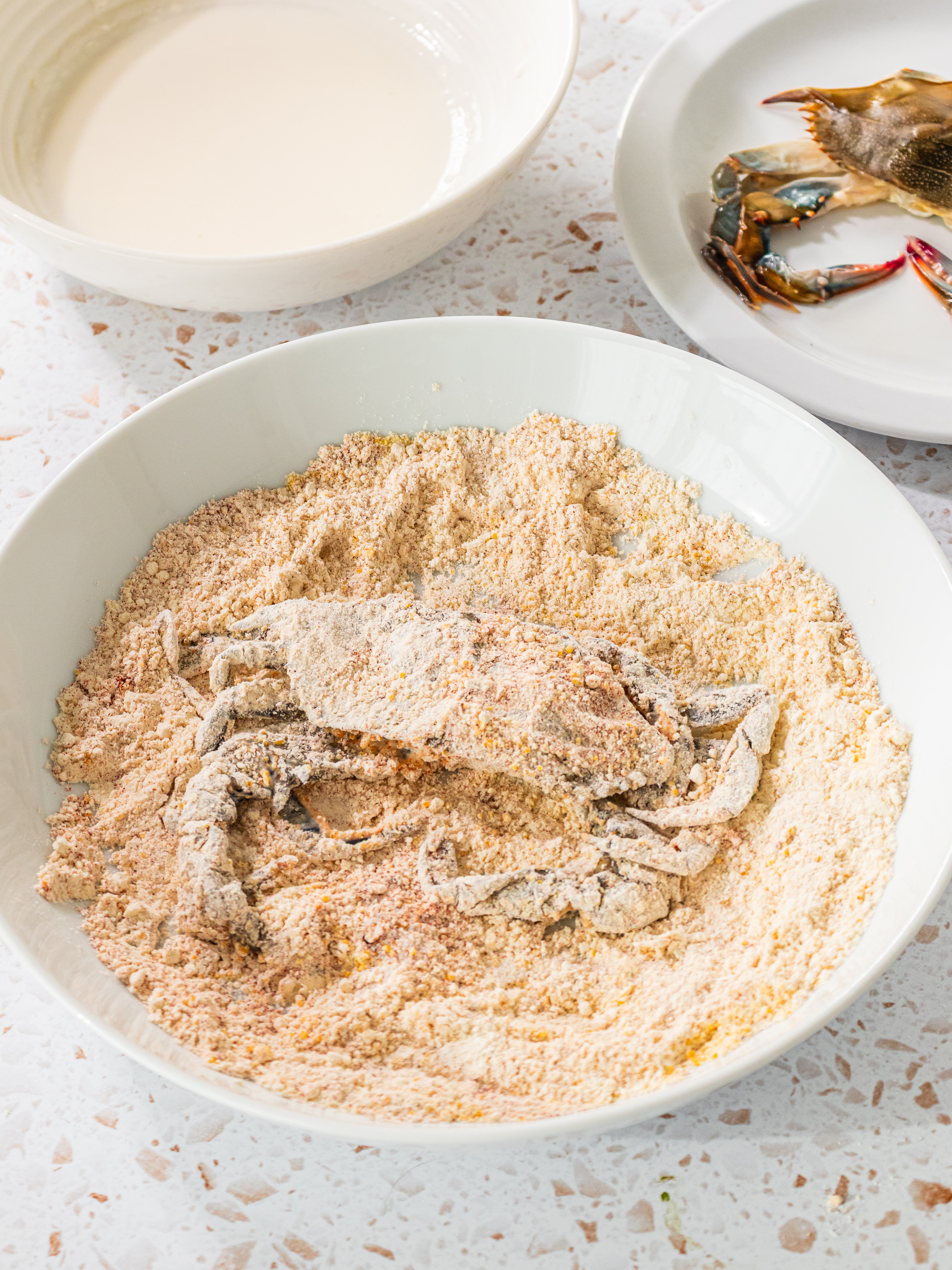 Image of Coat crab in buttermilk allowing excess to run back into...
