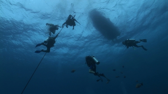 Scuba divers and decompression stop under the diving boat, Moorea