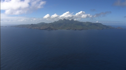 Aerial shot of the island Ua Pou in Marquesas Archipelago, from ocean, the mountains under clouds