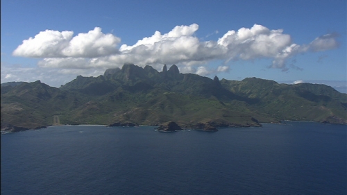 Aerial shot of the island Ua Pou in Marquesas Archipelago, from ocean, mountains under clouds