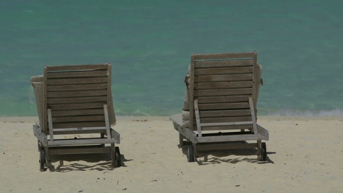Bora Bora,  Two long chairs on the white sand beach