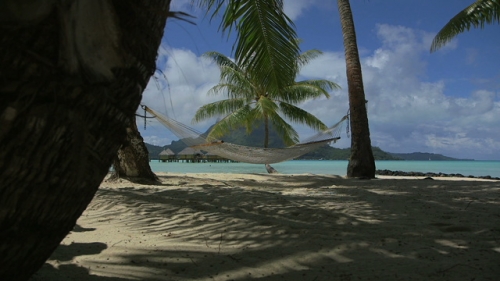 Bora Bora, Hamac installed between trees on the white sand beach, view on the lagoon
