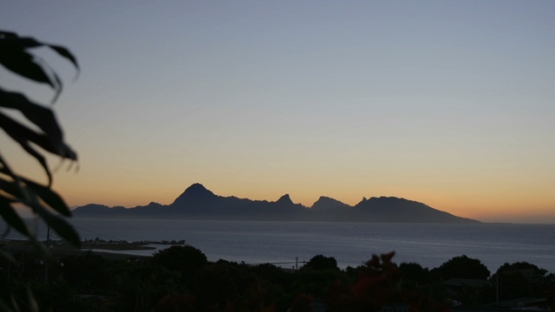 Moorea, very nice and orange sunset behind the mountain chain of the island, shot from Tahiti