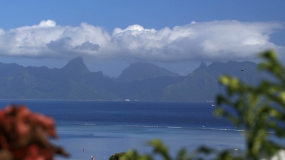 Moorea shot from Tahiti, view of the island under blue sky and clouds, zoom