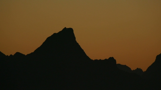 Moorea, nice sunset on the mountain with a hole, under orange sky, shot from Tahiti