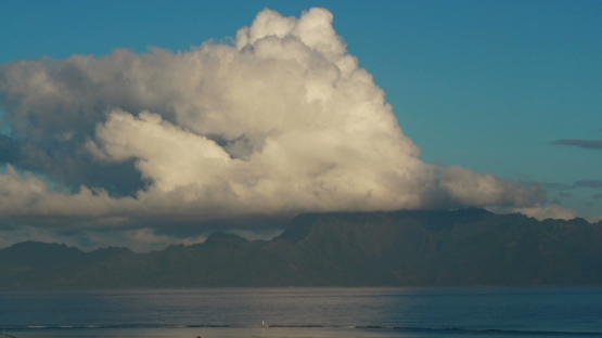 Timelapse, big cloud on the island Moorea under sunrise light, reflected on the ocean