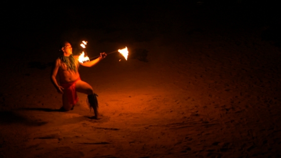 Slowmotion, fire dancer juggling torches on the sand beach at night