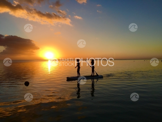 Moorea, Two children paddling through the sunset at Hauru beach 