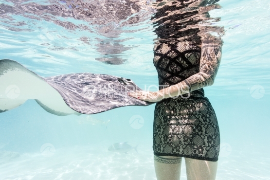 Woman caressing a sting ray underwater, in the lagoon
