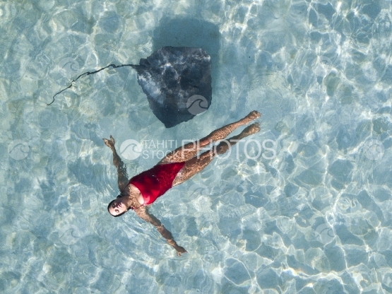 Moorea, Sting ray swimming around a woman in the lagoon, aerial view