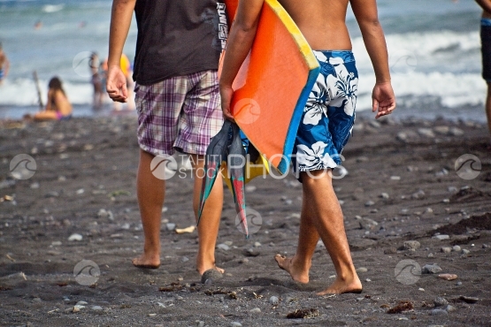 Tahiti, two young men walking on the beach with their body board
