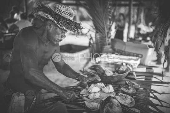 Bora Bora, Old tahitian with hat setting up the meal on the table