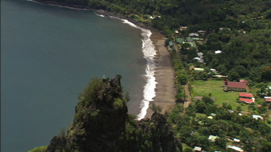 Aerial view of Nuku Hiva, over the village of Hatiheu aand its statue on the rock