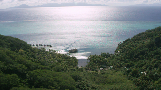 Aerial view of Huahine, Leeward islands, overwater hotel behind hills, 4K UHD