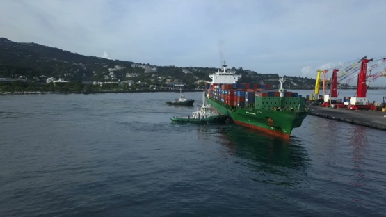 Tahiti, aerial video drone of cargo ship and tug boat in Papeete harbour