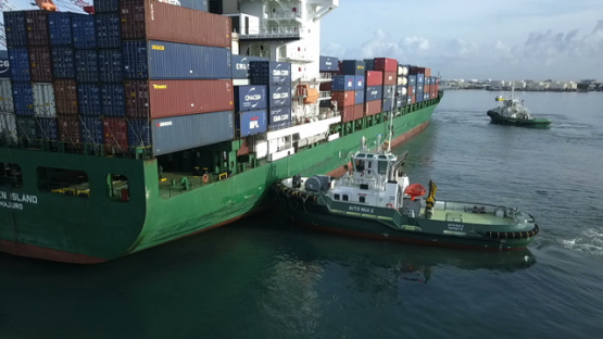 Tahiti,  aerial video drone of cargo ship with containers on board in the harbour of Papeete