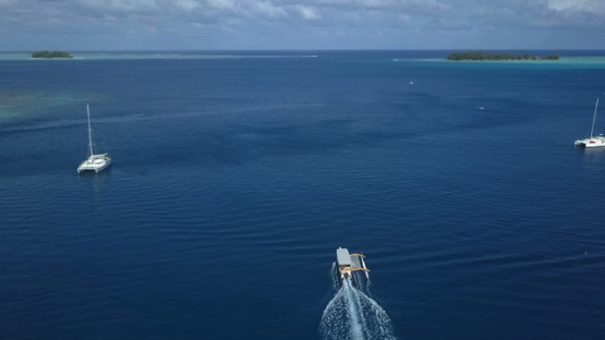 Bora Bora, aerial drone video following an outrigger boat in the lagoon, leeward islands, Polynesia