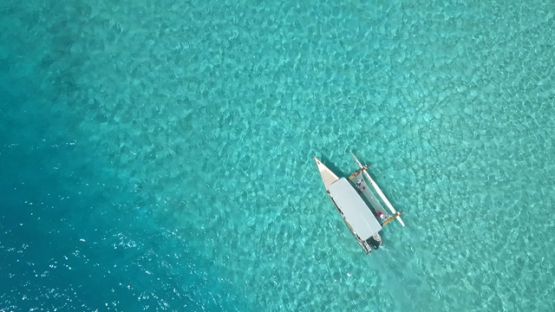 Bora Bora, aerial drone video, above outrigger boat in the lagoon,  leeward islands, Polynesia