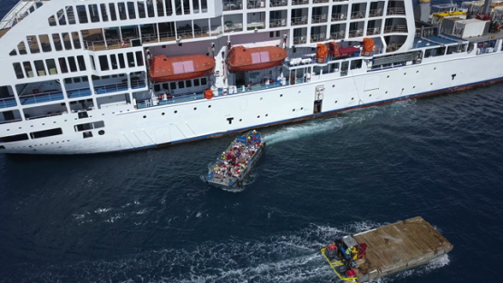 Bora Bora, aerial drone video of a cruise ship moored in the lagoon, passengers on the barge, leeward island, polynesia 4K UHD