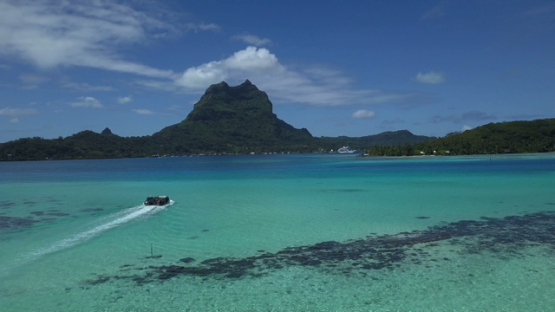 Bora Bora, aerial drone video of a barge navigating in the lagoon, leeward island, polynesia 4K UHD